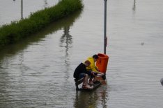 Zwei Kinder sitzen auf einer Bank von Hochwasser umgeben.