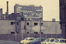 Straßenszene in Ostberlin in Mauernähe mit geparkten Wartburg- und Trabant-Pkws; Hinterlandmauer in der Schützenstraße, Ecke Charlottenstraße; im Hintergrund das Axel-Springer-Hochhaus in West-Berlin