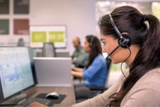 Profilbild einer Mitarbeiterin in einem Call Center mit Headset und PC