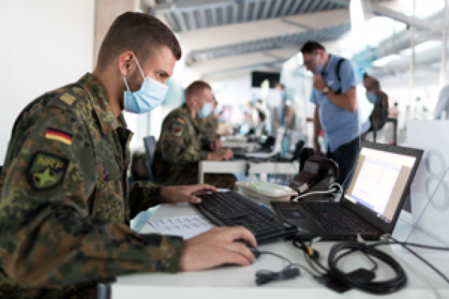 Soldaten mit medizinischen Atenschutzmasken arbeiten an Computern in einer großen Klinik
